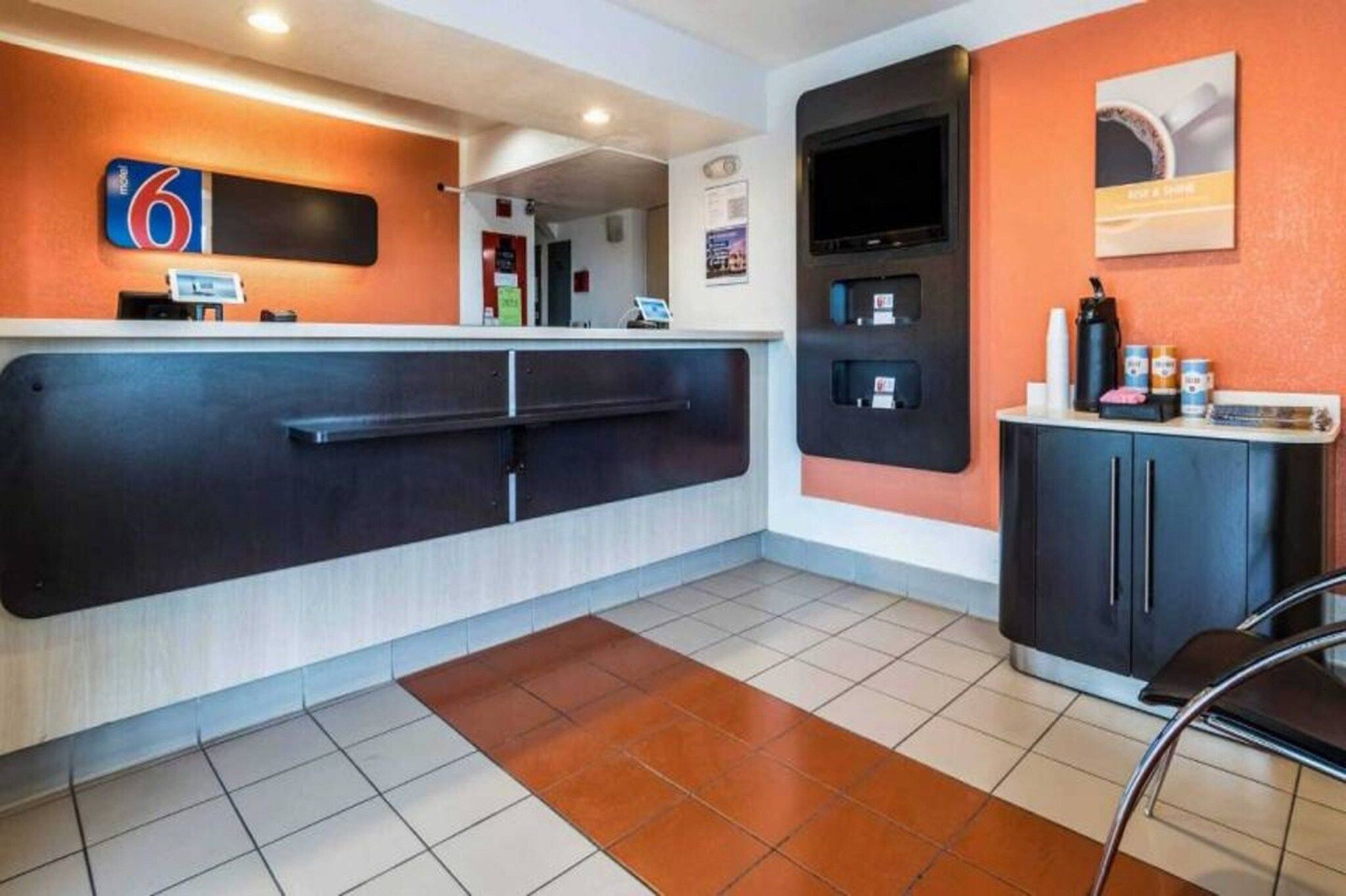 A hotel reception area with a counter, a coffee machine, and a seating area.