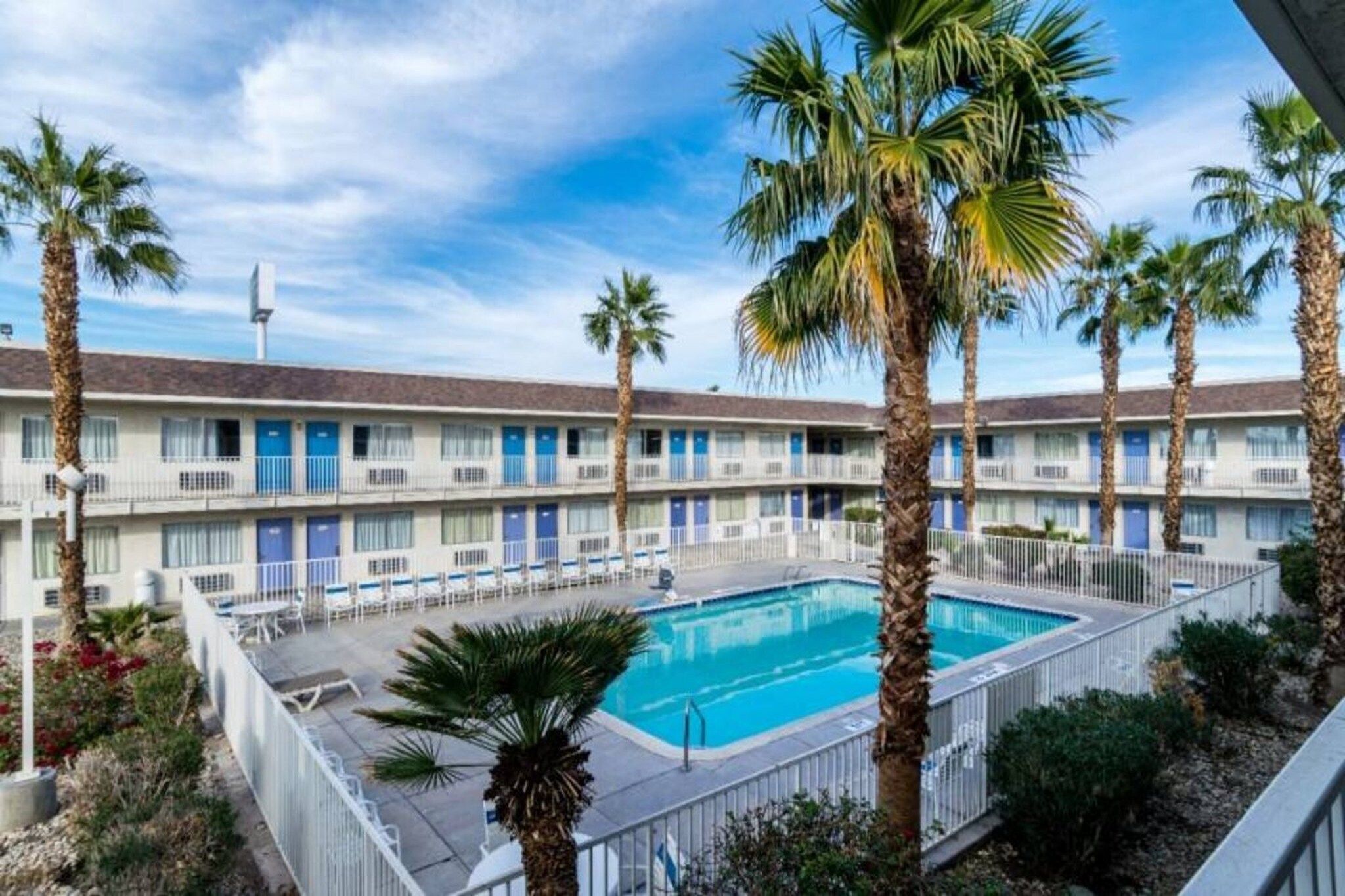 A motel with a swimming pool surrounded by palm trees.