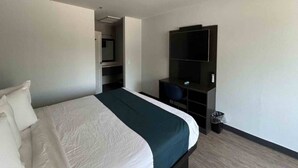 Ein Hotelzimmer mit einem Bett, einem Schreibtisch, einem Stuhl, einem Fernseher und einem Mülleimer.