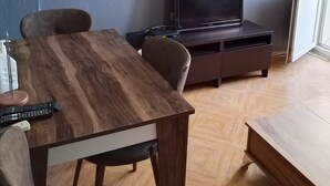 Ein modernes Wohnzimmer mit Esstisch aus Holz, einer Couch, einem Flachbildfernseher und einer eingebauten Klimaanlage.
