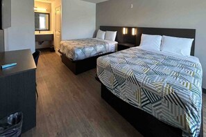 Une chambre d’hôtel avec deux lits, un bureau et un miroir.