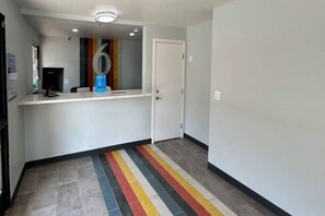 Un couloir avec un comptoir d’accueil, une porte et un tapis rayé aux couleurs vives.