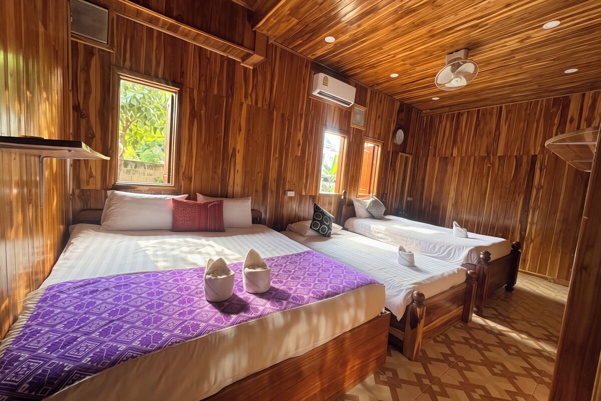 A wooden room with two beds, a window, and an air conditioning unit.