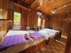 A wooden room with two beds, a window, and an air conditioning unit. - Khemphet Douangsavath Guesthouse (Luang Prabang)