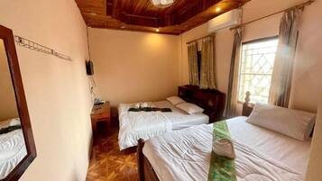 Habitación de hotel con dos camas, techo de madera, un ventilador y una ventana con cortinas.