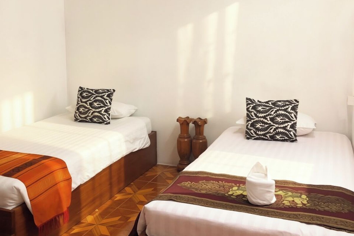 Habitació d'hotel amb dos llits, sostre de fusta i una manta estampada als llits.