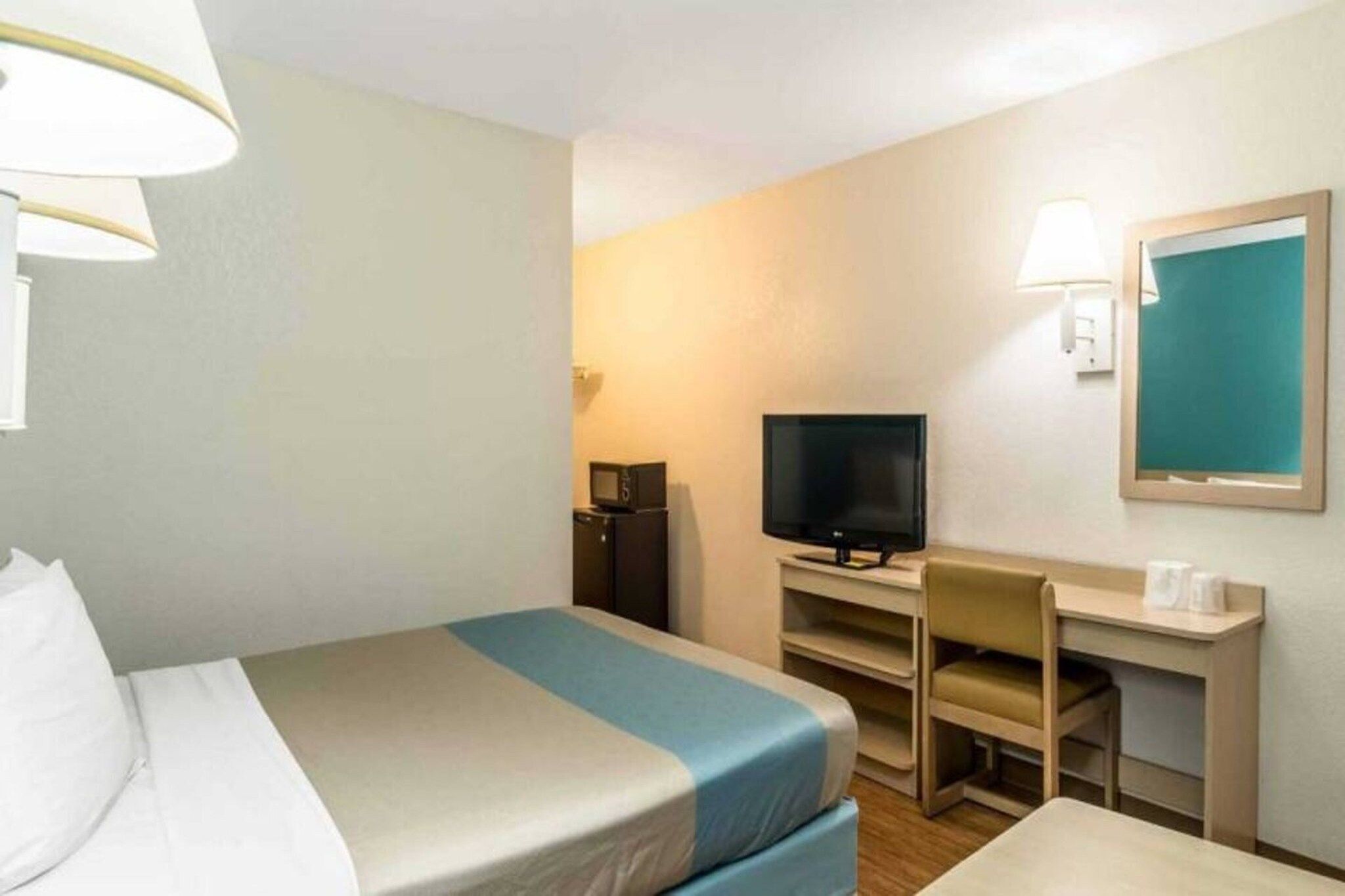 A hotel room with a bed, a desk, a television, and a chair.