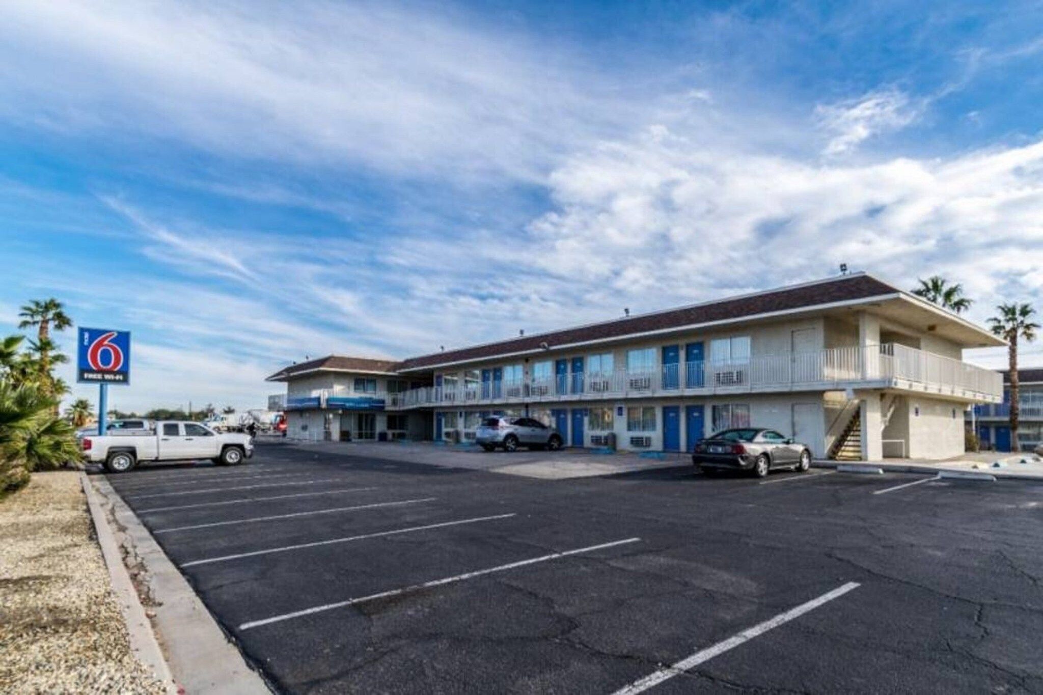 A motel with a parking lot, a sign indicating free Wi-Fi, and a two-story building with balconies.