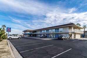 A motel with a parking lot, a sign indicating free Wi-Fi, and a two-story building with balconies.