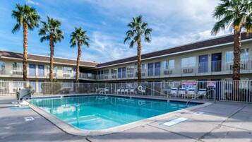 Ein Hotel mit Swimmingpool, Palmen und einem eingezäunten Deckbereich.