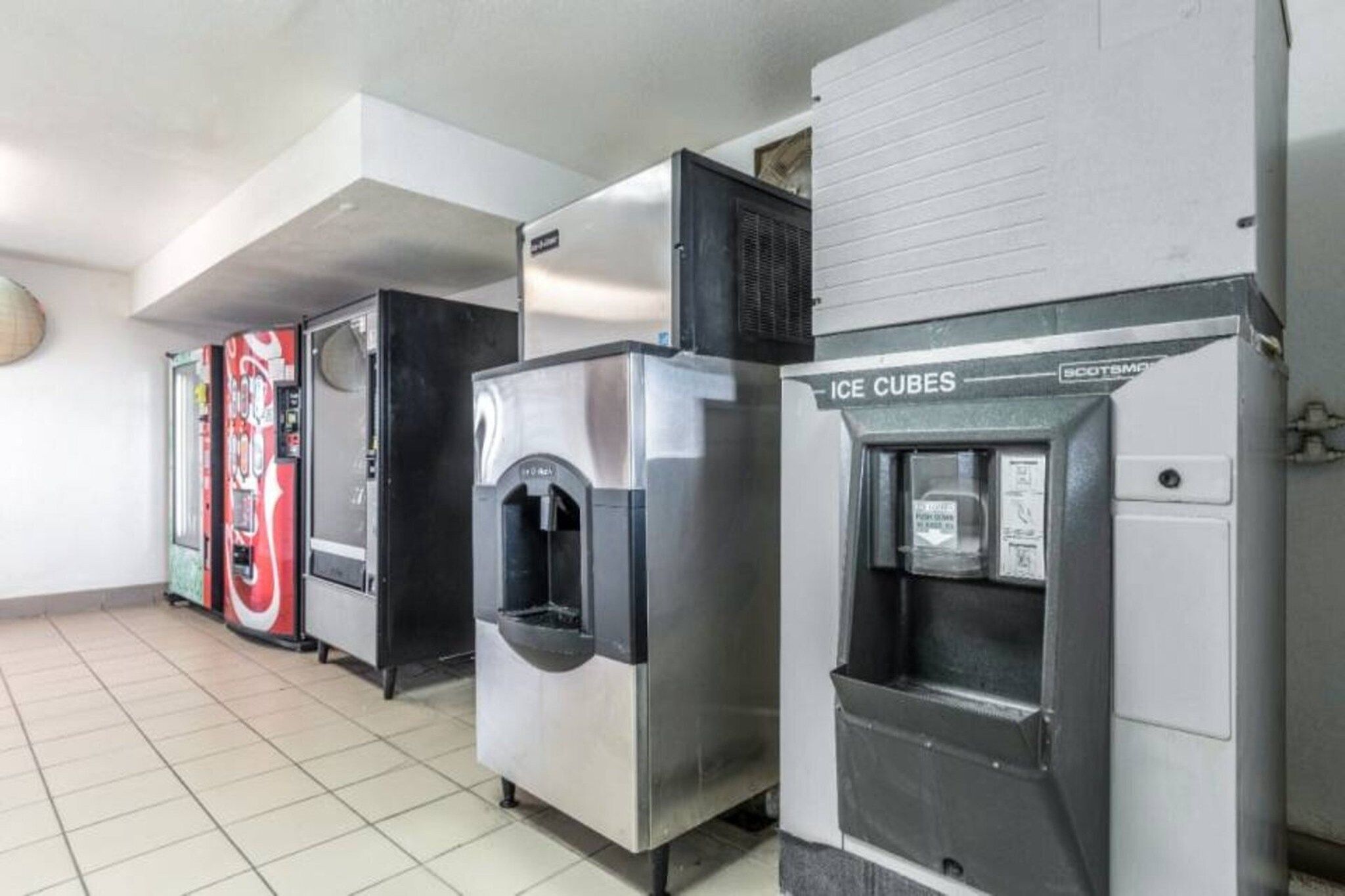 A row of vending machines, including a Coca-Cola cooler and an ice dispenser.