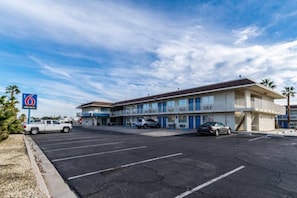A motel with a parking lot, a sign indicating free Wi-Fi, and a two-story building with balconies.