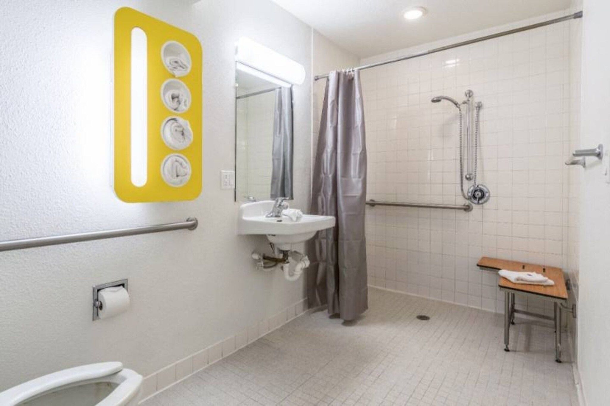 Un baño con ducha, lavabo, inodoro y un banco.
