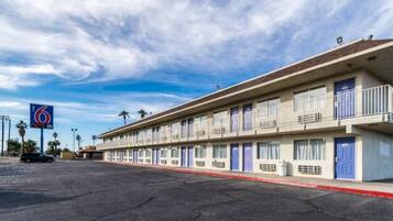 Ein Motel mit einer Reihe von Zimmern, einem Parkplatz und blauem Himmel.