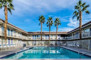 Ein Hotel mit Schwimmbad, Palmen und blauem Himmel.