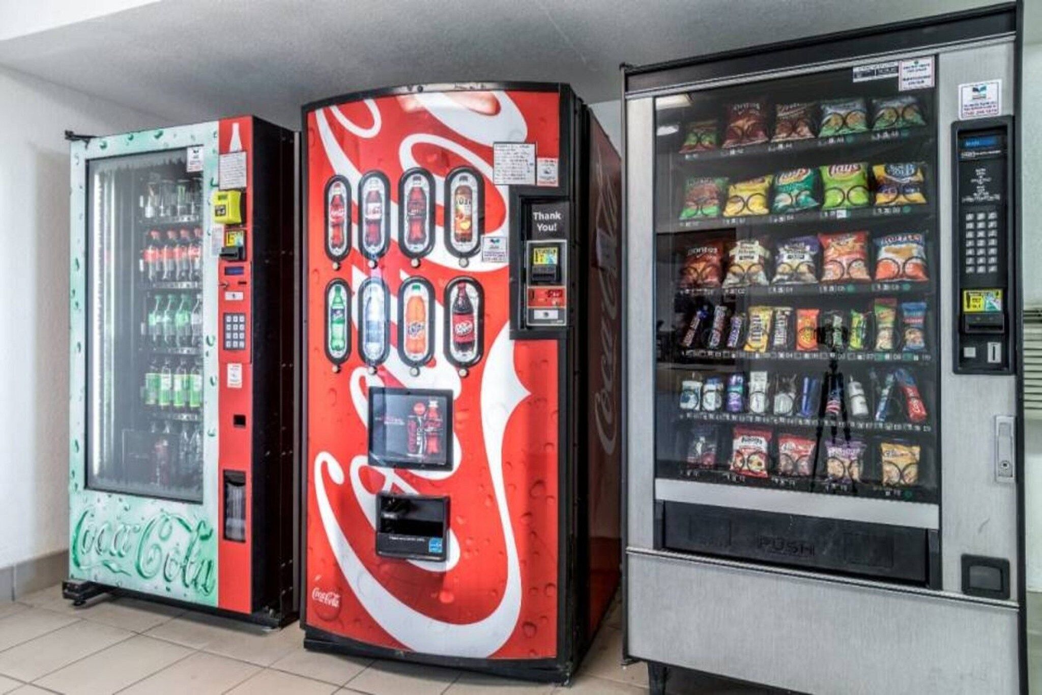 Three beverage vending machines with various drink options.