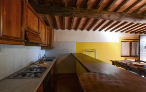 A kitchen with wooden cabinets, a gas stove, and a yellow accent wall. - Cozy apartment in Murlo with swimming pool (Murlo)