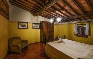 A room with a bed, a chair, a wardrobe, and two framed pictures on the wall. - Cozy apartment in Murlo with swimming pool (Murlo)