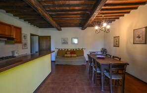 A kitchen with wooden cabinets, a stove, and a dining area with a table and chairs. - 2 bedroom lovely home in Murlo (Murlo)