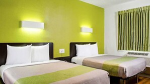 Una habitación de hotel con dos camas, paredes verdes y una ventana con cortinas.