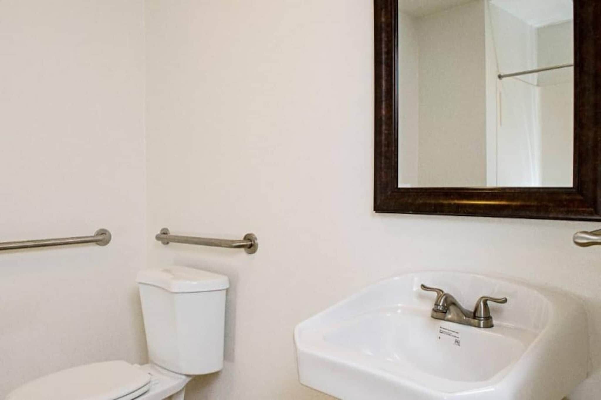 A bathroom with a toilet, a sink, and a mirror.