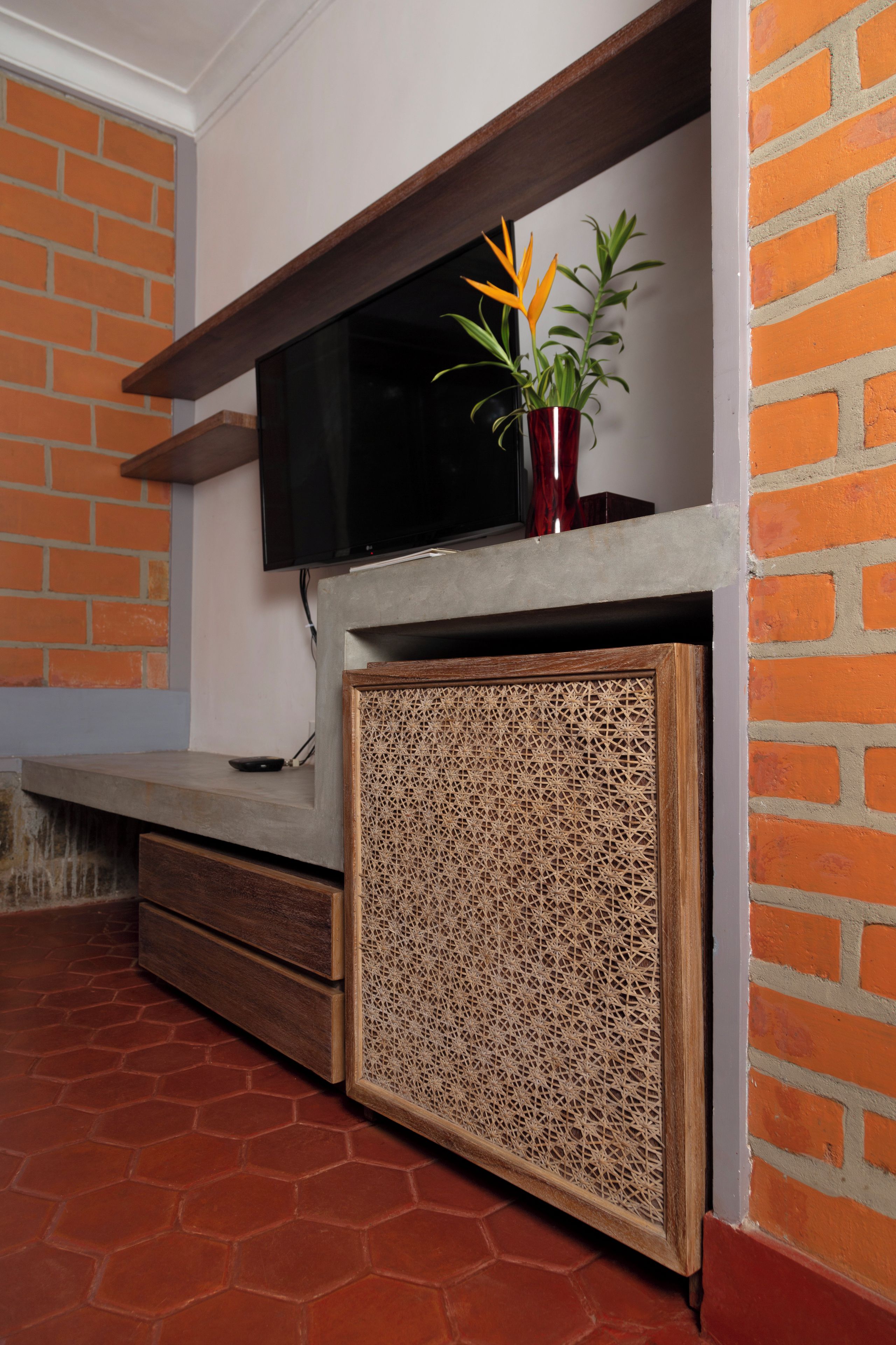 Un televisor de pantalla plana montado en una pared con diseño de ladrillo y un mueble de madera debajo.