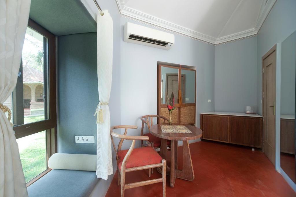A room with a dining table, chairs, a mirror, and a wardrobe.