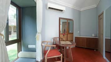 A room with a dining table, chairs, a mirror, and a wardrobe.
