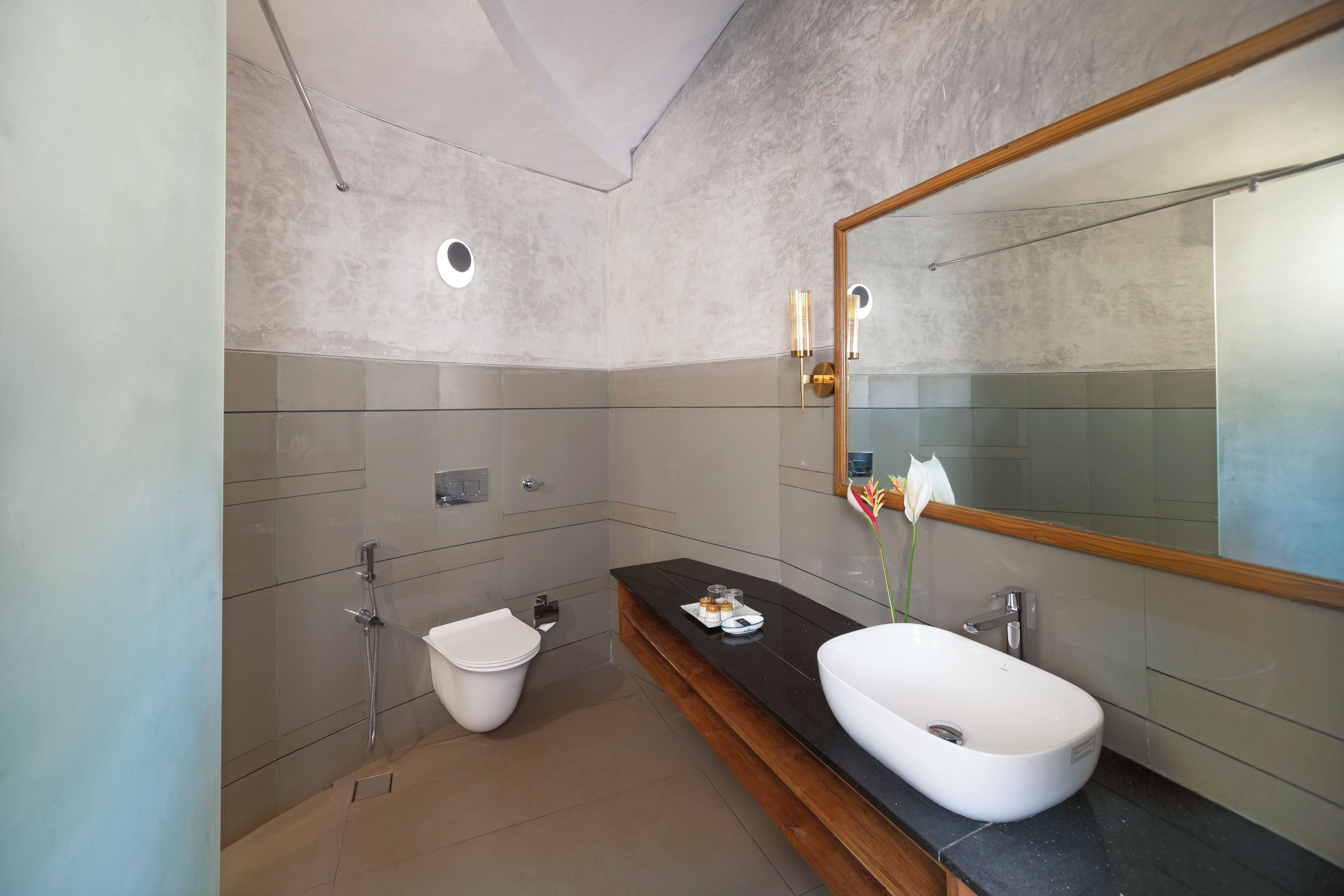 Un baño moderno con un espejo grande, un lavamanos blanco y un inodoro.