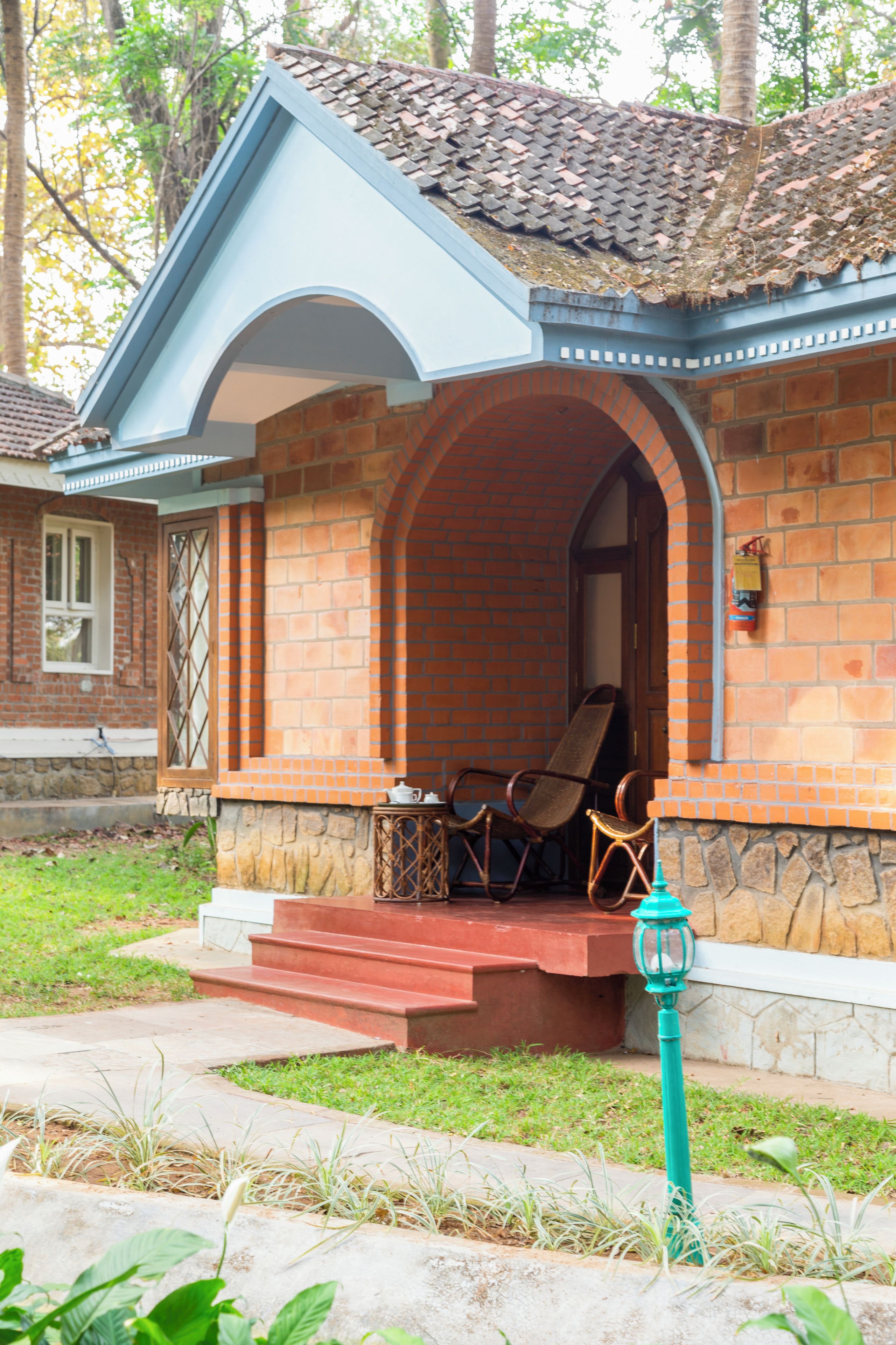 Ein Haus mit Backsteinfassade, einem Ziegeldach und einer Veranda mit zwei Stühlen.