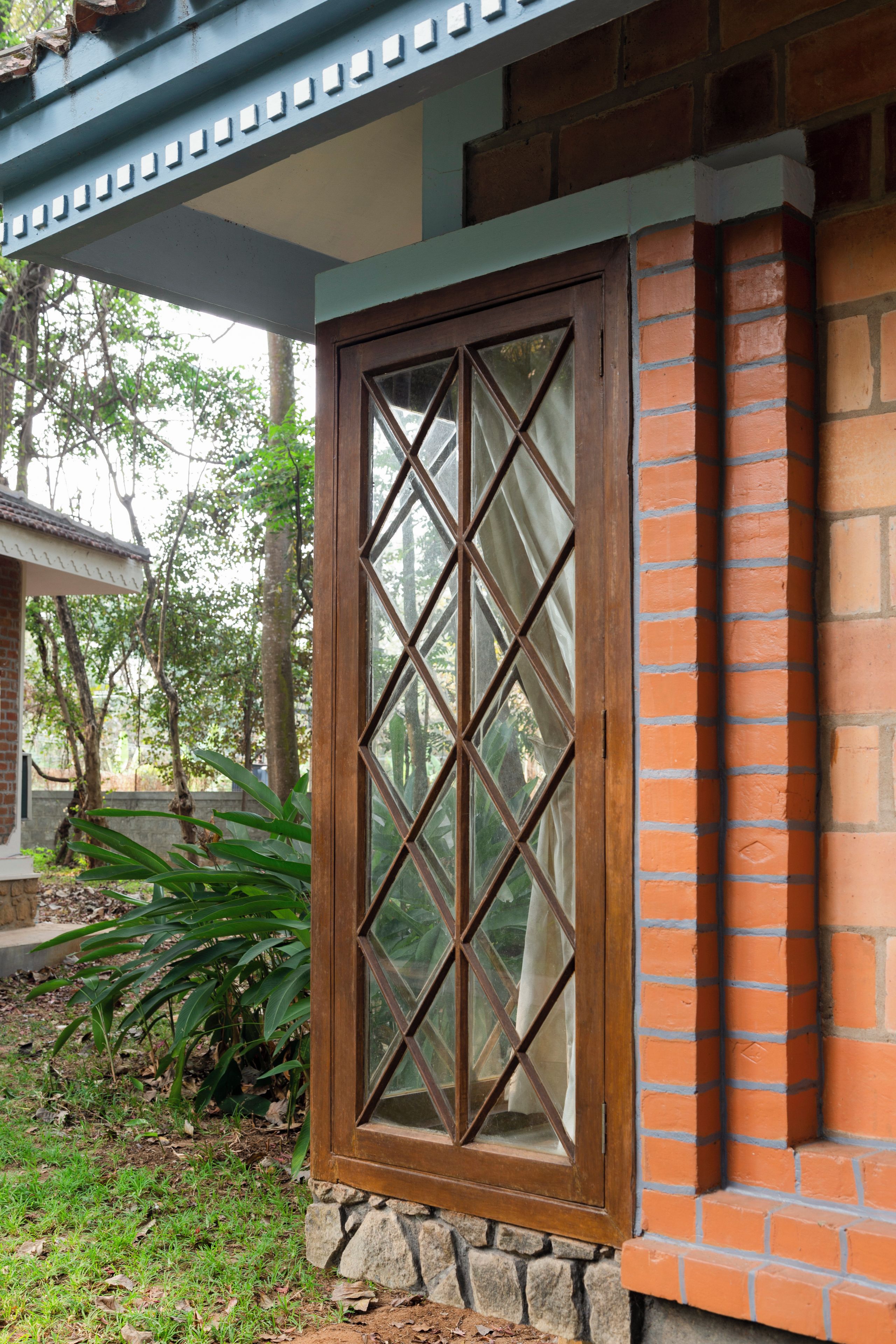 A window with a diamond pattern, a brick wall, and a stone base.