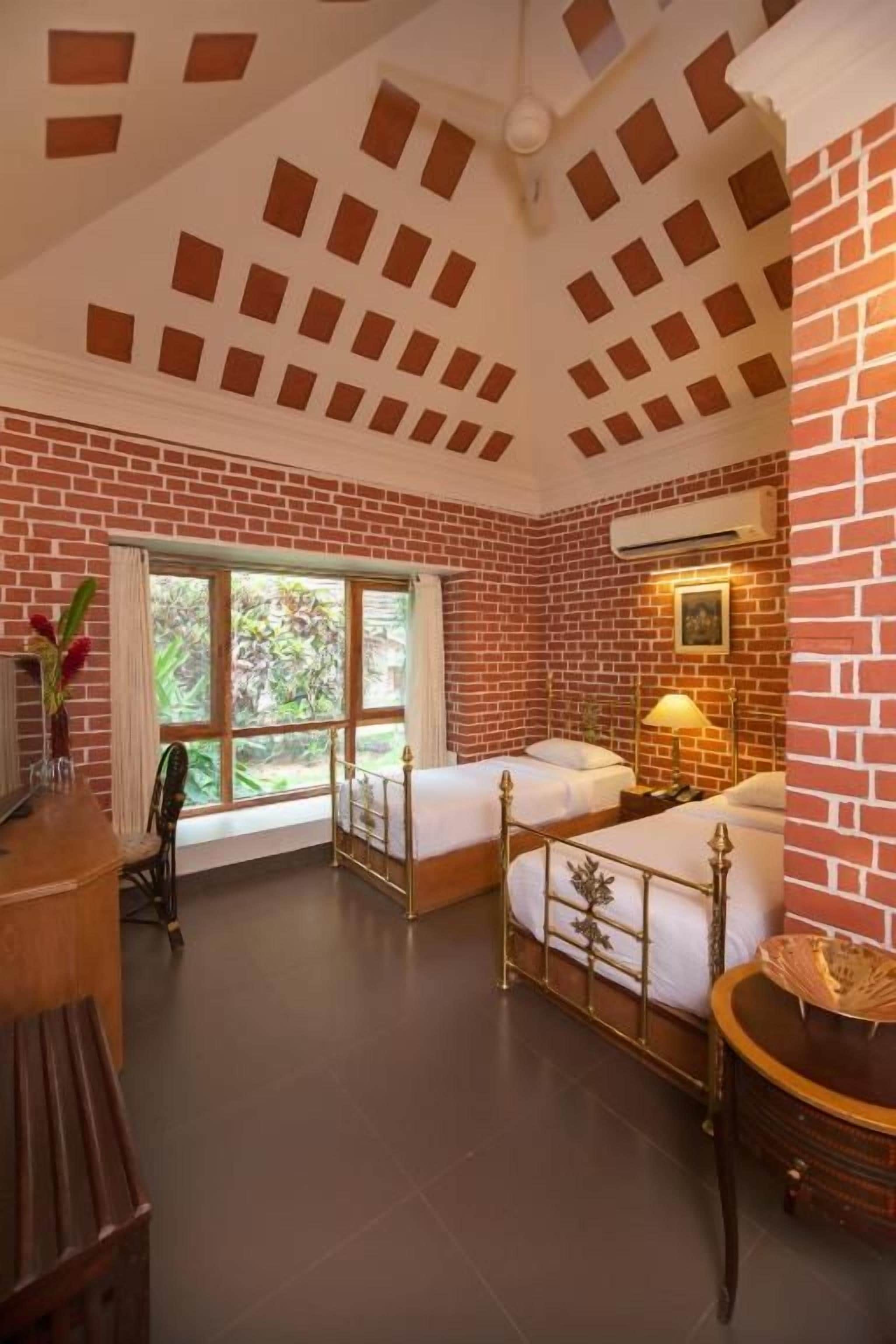 A room with two beds, a desk, and a window.