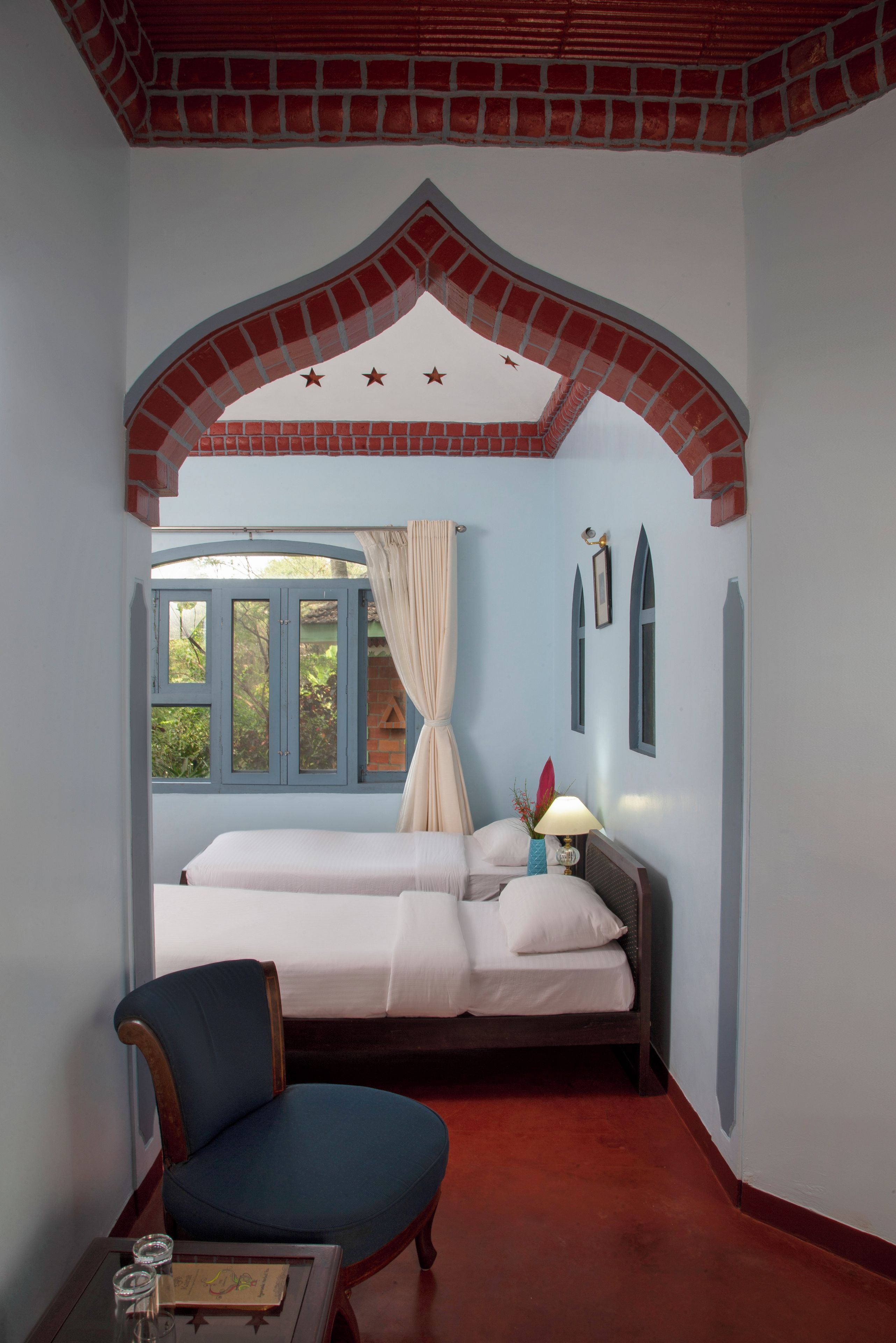 Ein Zimmer mit einem Bett, einem Sessel, einem Tisch, einem Fenster und einem dekorativen Bogen.