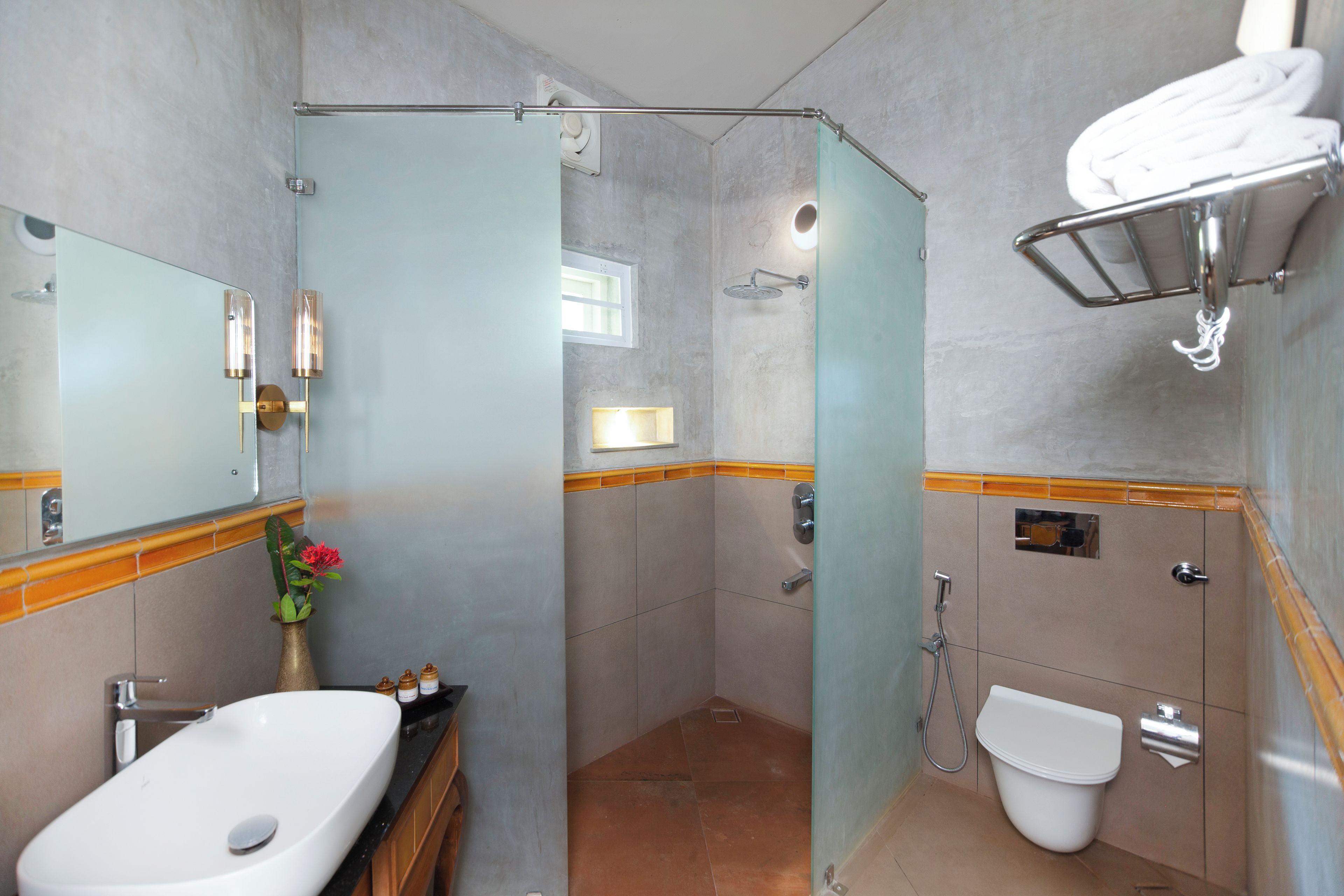 Un baño moderno con ducha envuelta en vidrio, un lavabo blanco y un inodoro.