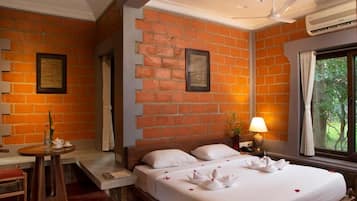 Habitación de hotel con pared de ladrillo, cama con ropa blanca, mesita de noche con lámpara y ventana con cortinas.
