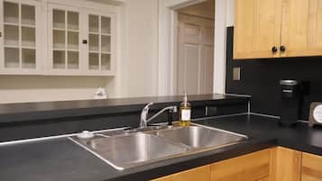 A kitchen with a double sink, a coffee maker, and wooden cabinets.