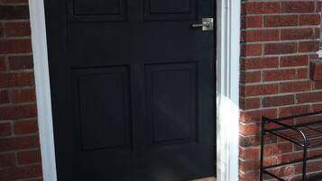 Une porte en bois sombre, dotée d’une poignée en métal et d’un paillasson sur lequel est écrit le mot « BIENVENUE ».