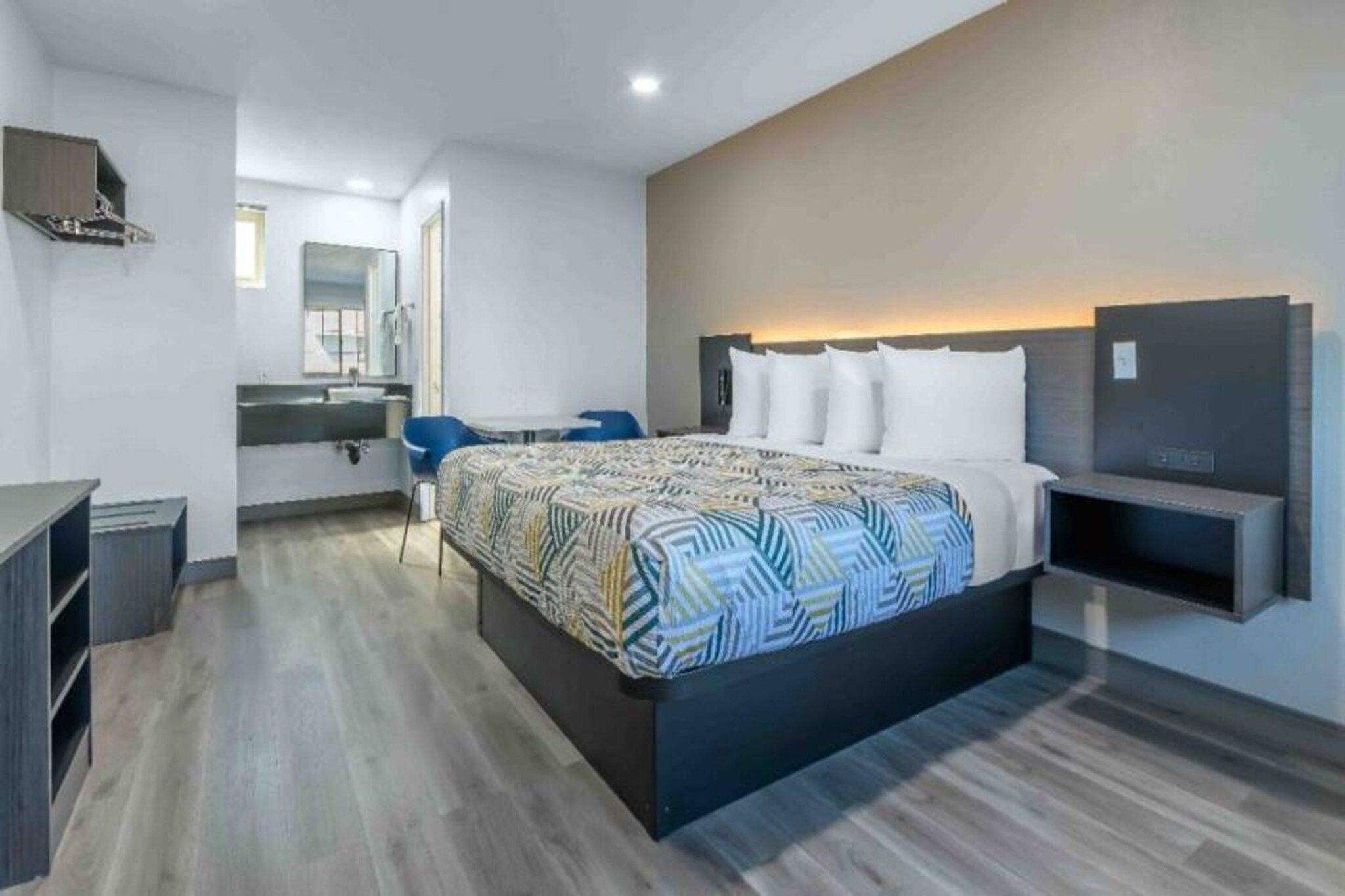 Habitación de hotel moderna con una cama grande, un escritorio, una silla, un televisor y un baño.