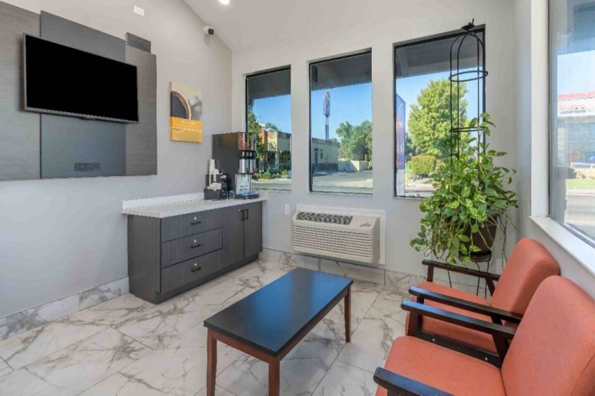 A modern interior with a flat-screen TV, a coffee machine, a plant, and a seating area with a table.