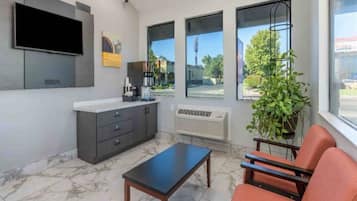 A modern interior with a flat-screen TV, a coffee machine, a plant, and a seating area with a table.