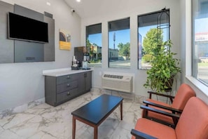A modern interior with a flat-screen TV, a coffee machine, a plant, and a seating area with a table.