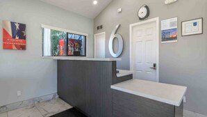 Un área de recepción con mostrador, un reloj y una puerta.