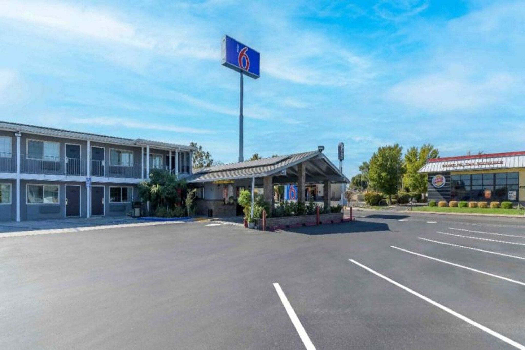 Een parkeerplaats met een gebouw, voorzien van een blauw bord met het nummer 6.