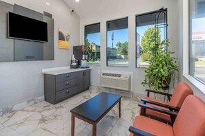 A modern interior with a flat-screen TV, a coffee machine, a plant, and a seating area with a table.