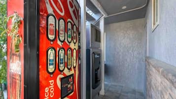 Ein Getränkeautomat mit verschiedenen Auswahlmöglichkeiten, ein Kühlschrank und eine Treppe, die in eine obere Ebene führt.