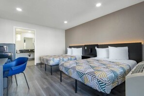 A hotel room with two beds, a desk, and a chair.