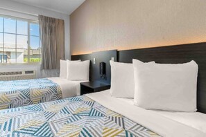 Een hotelkamer met twee bedden, een groot raam en uitzicht op buiten.