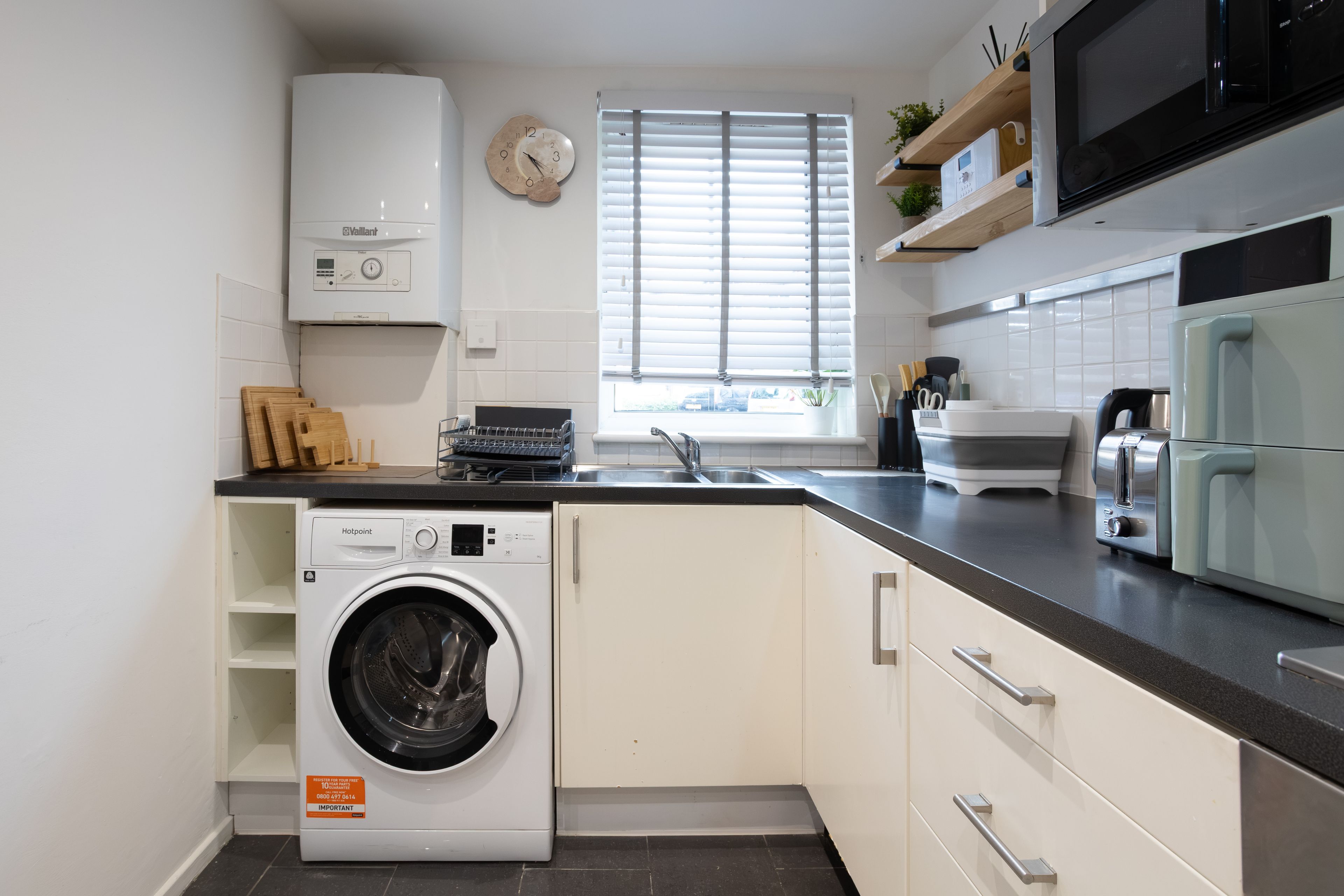 A compact kitchen with a built-in washer, a microwave, and a sink.
