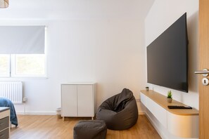 A modern living room with a flat-screen TV, a bean bag chair, a small cabinet, and a radiator. - Contemporary 2BDR House with Garden in New Cross (Greater London)