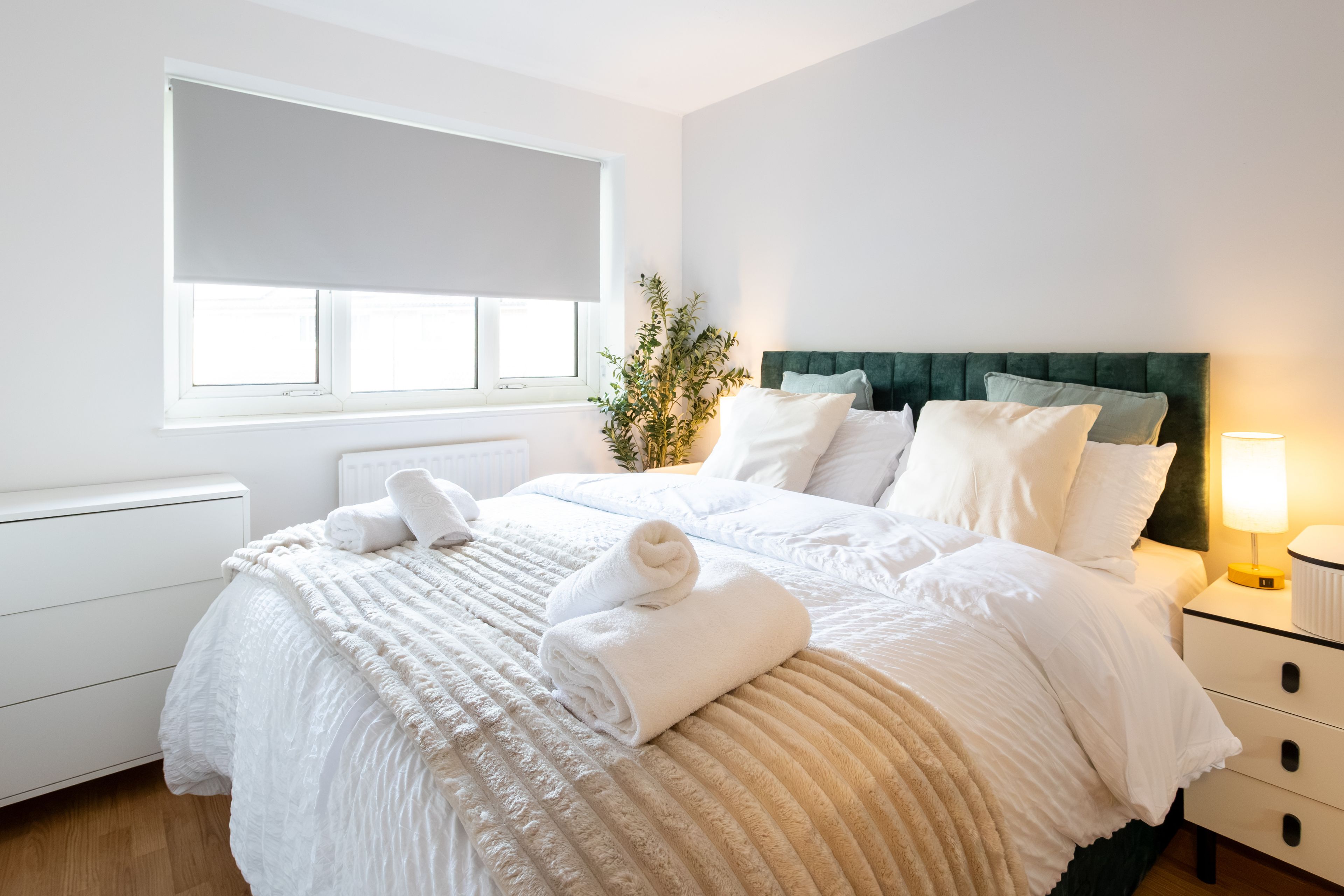 A hotel room with a bed, bedside tables, a lamp, and a window.